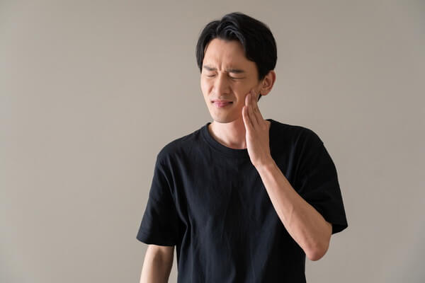 歯に痛みを感じる男性